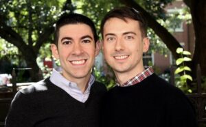 Two men smiling in front of a tree.