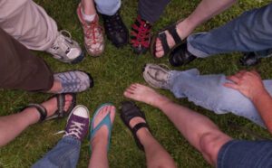 A group of people standing in a circle wearing sandals.