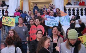 A group of people holding signs on the steps of a building.