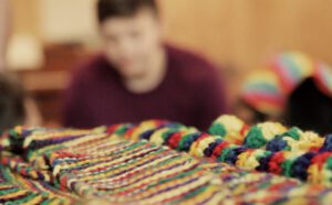 A group of people sitting around a table with colorful blankets.