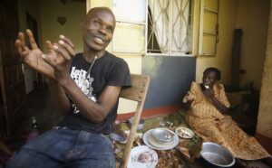 A man sits on the floor with a plate of food.