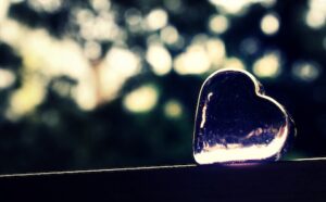 A heart shaped glass sitting on top of a wooden railing.