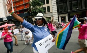 A woman in a pink shirt waving a flag in a parade.