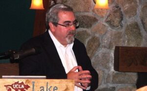 A man standing at a podium in front of a stone wall.