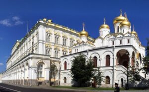 A white building with gold domes on the side of the road.