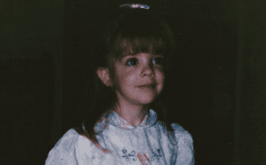 A little girl in a white dress holding a frisbee.