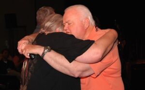 A man and woman hugging each other at a concert.