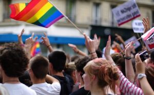 A group of people waving rainbow flags in a crowd.