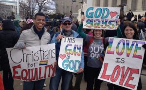 A group of people holding signs that say god says gay is love.