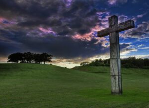 A cross in the middle of a grassy field.