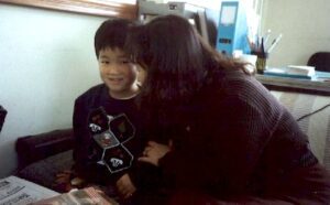 A woman sitting on a couch with a young boy.