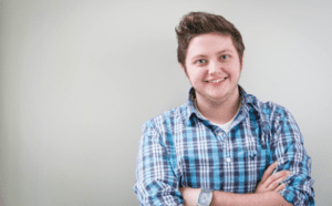 A young man in a plaid shirt with his arms crossed.