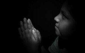 A black and white photo of a child praying.