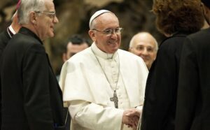 Pope francis shakes hands with a group of people.