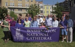 A group of people standing in front of a purple banner that says washington national cathedral.