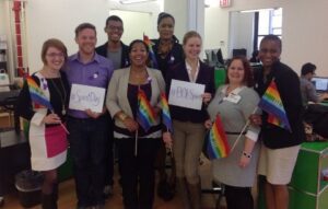 A group of people holding up rainbow flags in an office.