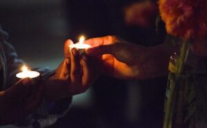 Two people holding candles in their hands at a candlelight vigil in san diego, california, on.