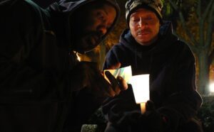 Two men holding a candle in the dark.