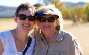 Two women in sunglasses posing for a photo in a field.