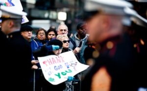 A group of people holding signs in front of a group of marines.