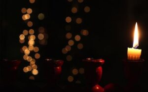 A lit candle in front of a bokeh background.