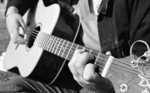 A black and white photo of a person playing an acoustic guitar.