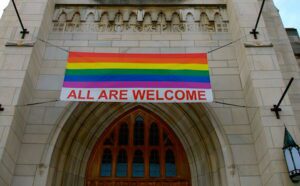 A rainbow flag hangs from the door of a church.