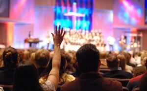 A group of people in a church raising their hands in the air.