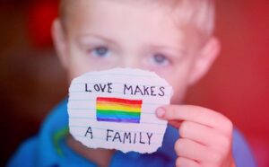 A young boy holding up a piece of paper that says love makes a family.