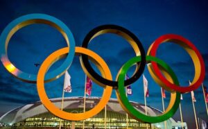 The olympic rings in front of a stadium.