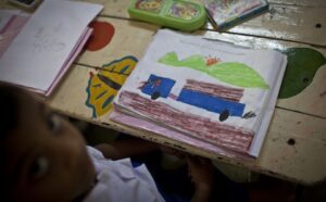 A child sits at a table with a drawing of a truck.