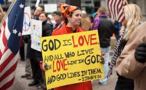 A woman holding a sign that says god is love.