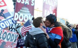 A group of people kissing in front of signs.