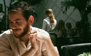 A man with a beard sitting at a table in a restaurant.