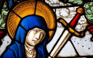 A stained glass window with a woman holding a sword.