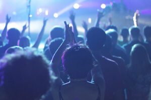 A crowd of people at a concert with their hands raised.