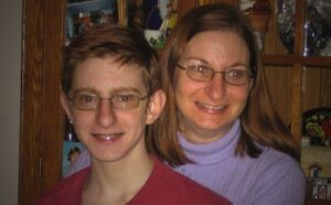 A woman with glasses and a boy posing for a photo.