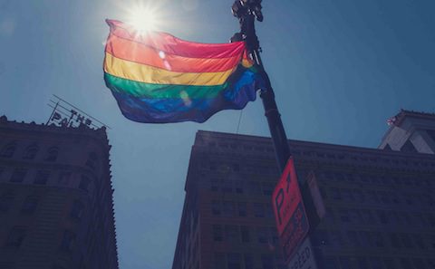 A rainbow flag is flying in front of a building.