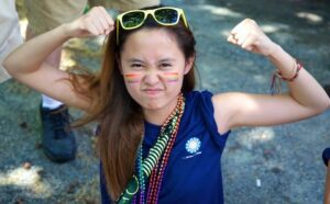 A woman with a rainbow painted face is posing for the camera.