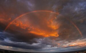 A rainbow is seen over a cloudy sky.