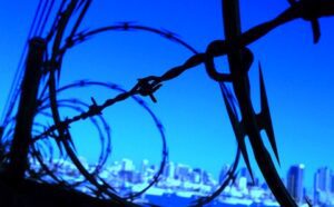 A barbed wire fence with a city skyline in the background.