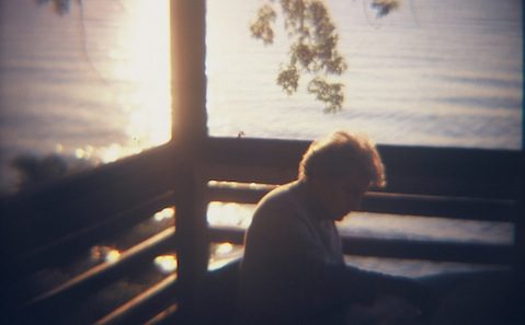 A woman sitting on a porch overlooking the water.