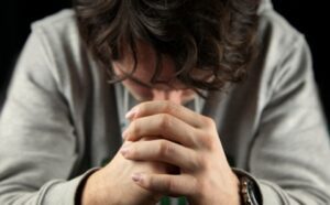 A man praying with his hands on his face.