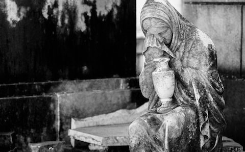 A black and white photo of a statue in a cemetery.