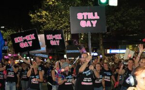 A group of people holding signs that say still gay.