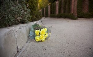 A bouquet of yellow flowers sits on the sidewalk.