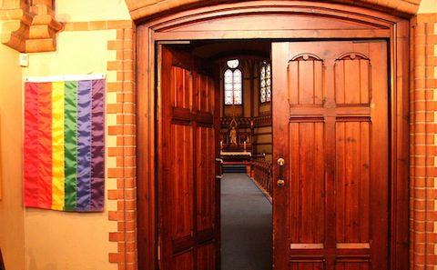 A wooden door with a rainbow flag on it.