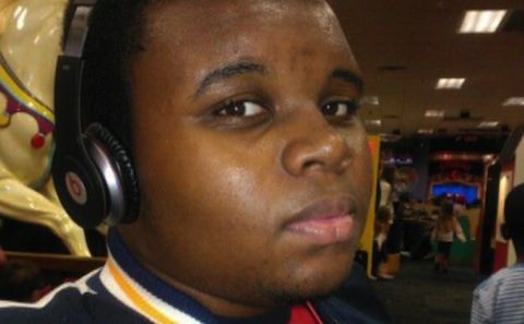 A young man wearing headphones in front of a carousel.