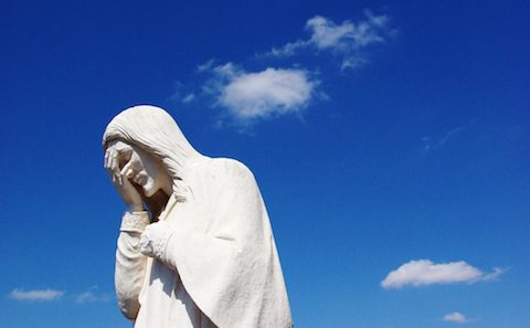 A statue of jesus in front of a blue sky.