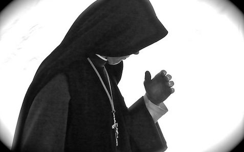 A black and white photo of a priest in a robe.